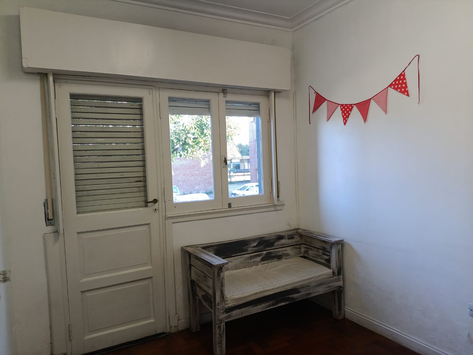 Rincón de la sala con un banco de madera y banderines rojos